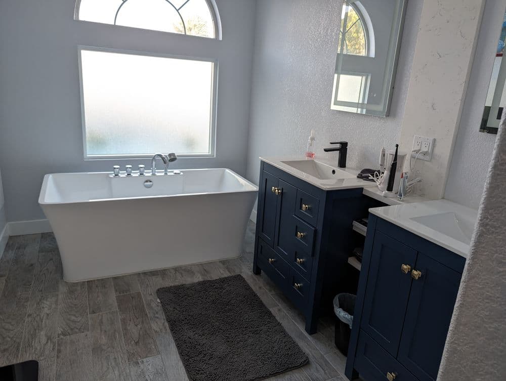 Modern bathroom featuring a freestanding bathtub, dual sinks, and elegant cabinetry.