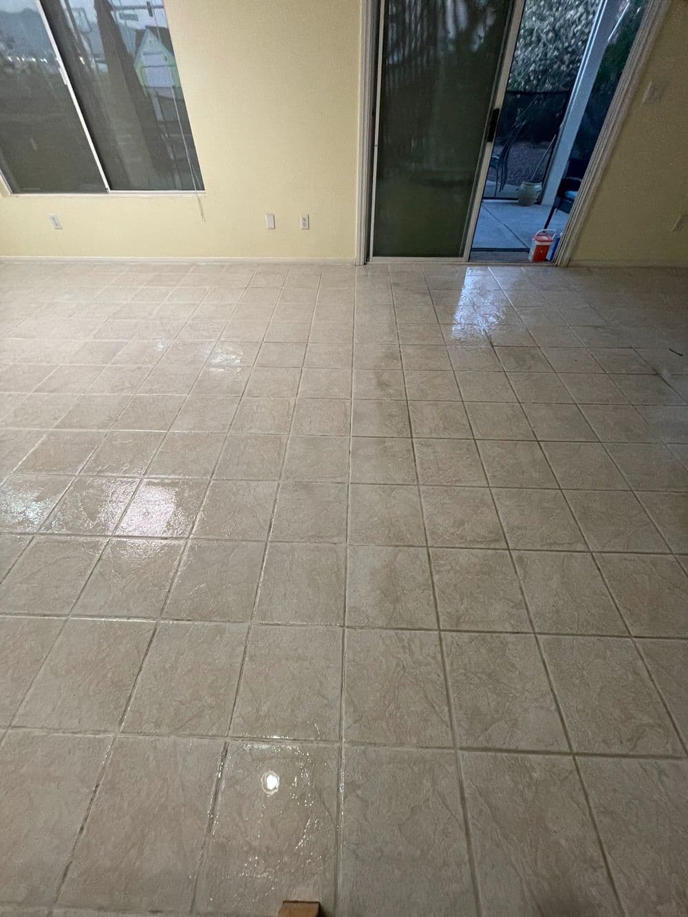 Shiny tiled floor in a bright room with a balcony visible through sliding doors.