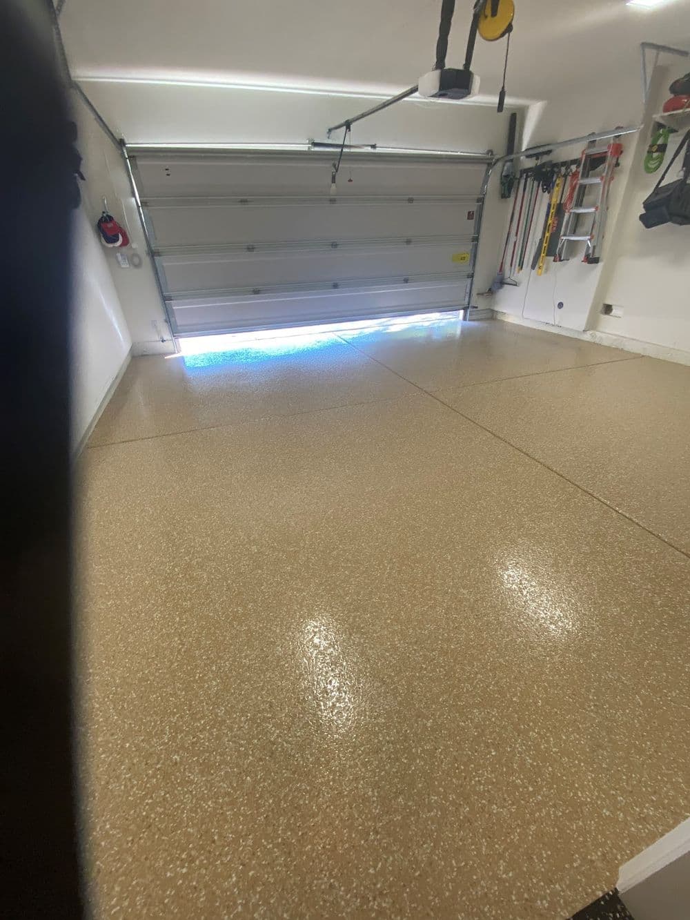 Clean, polished garage interior with open door showcasing concrete floor and organized tools.