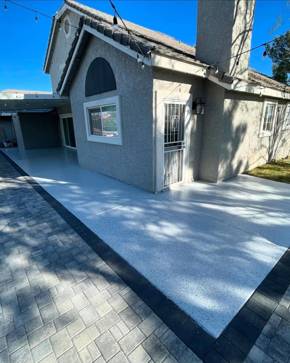 Modern house exterior with new concrete walkway and decorative outdoor lighting.
