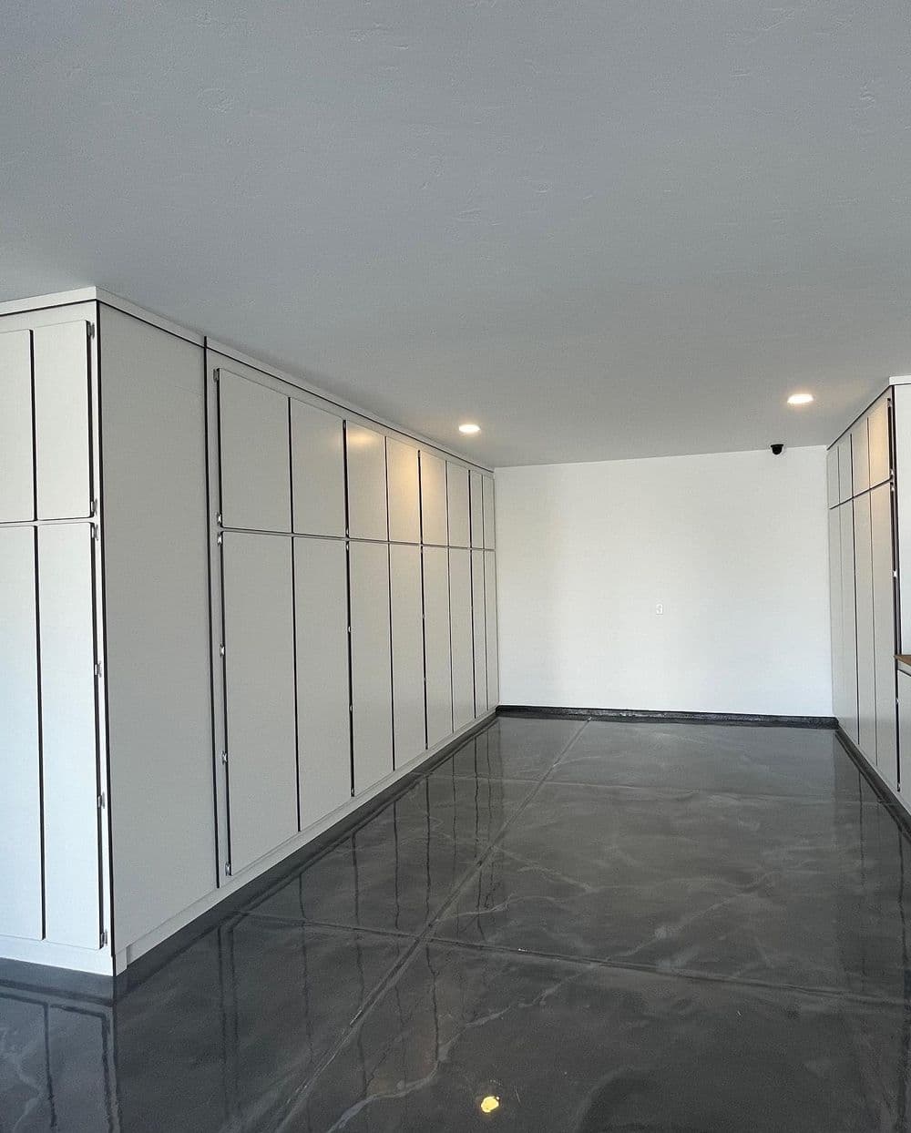 Modern garage interior featuring sleek storage cabinets and polished concrete flooring.