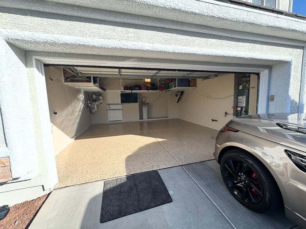 Spacious garage with polished flooring, neatly organized tools, and a parked car outside.